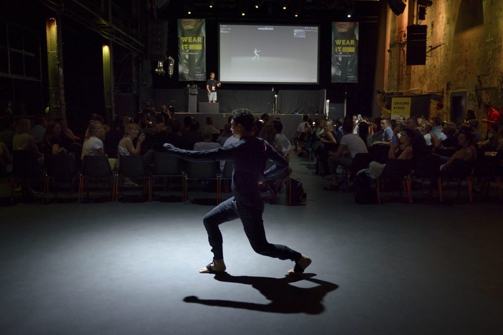 The image shows a demonstration of wearable technology presented at the Wear It Innovation Summit 2019.